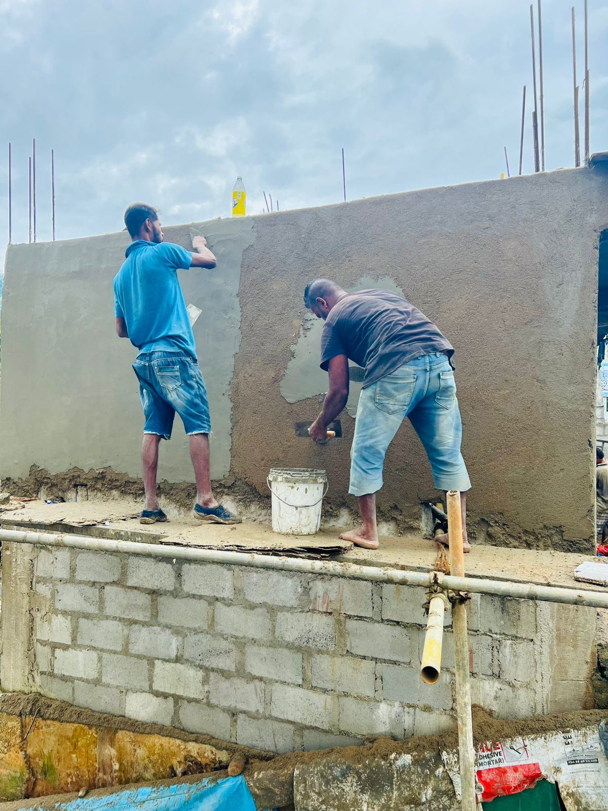 Masons plastering a concrete wall on a construction site