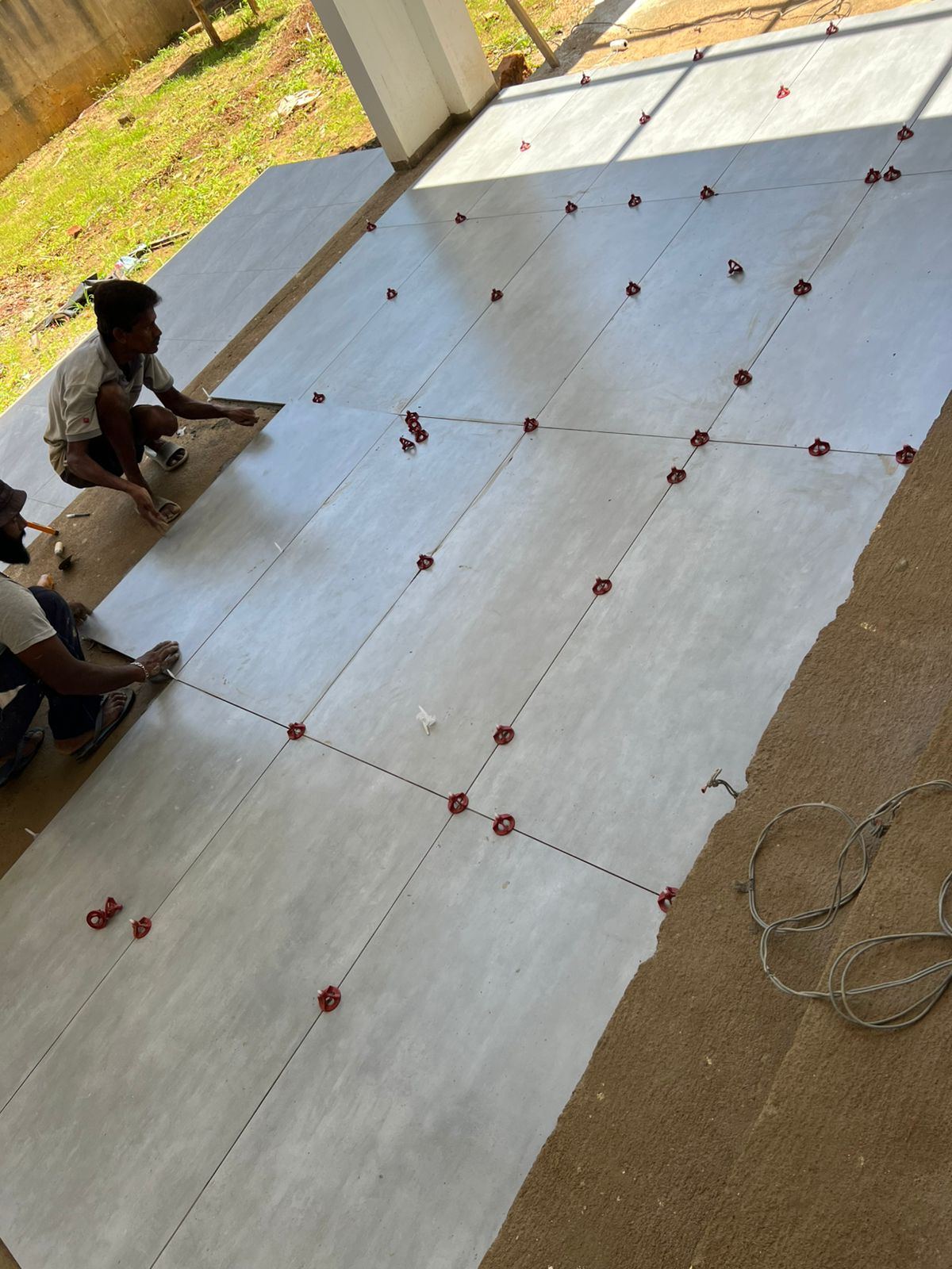 Floor tile laying with leveling clips on a freshly screeded floor